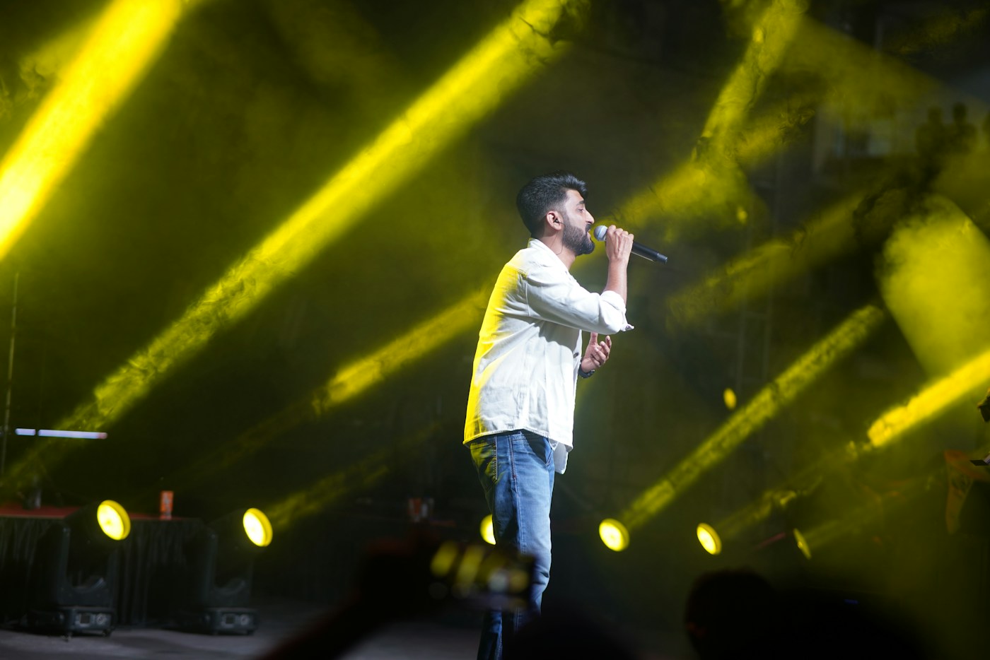 A singer performing beneath golden stage lights